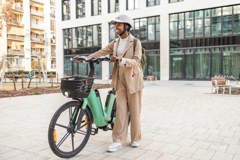A stylish black woman in an urban setting, confidently riding a bicycle, surrounded by modern