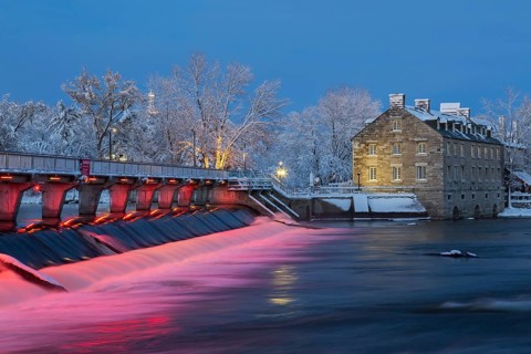 Illuminated Moulin Neuf water flow control dam and walkway over Des Mille-Iles river plus New Mill