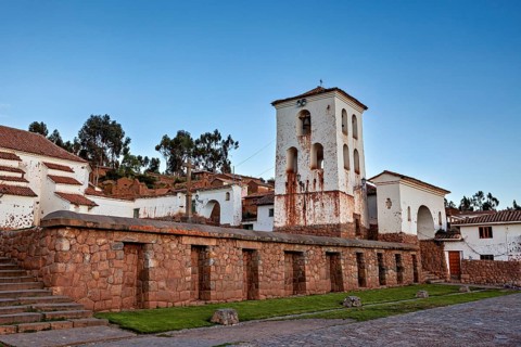 Colonial church tower and buildings with stone walls surrounded by nature in daylight, the historic