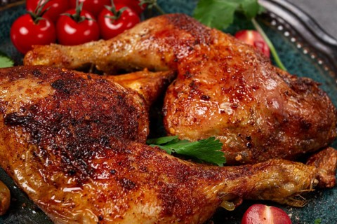 Grilled fried chicken legs, served with fresh cherry tomatoes and herbs, on a plate, homemade, no