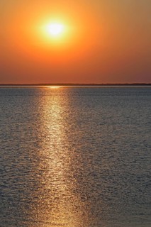 Sunset over the North Sea at low tide, the outline of the island of Juist on the horizon,