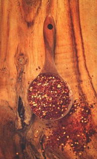 Red pepper flakes, in a wooden spoon, on a wooden table, rustic style, no people