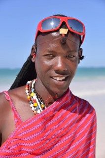 Young Maasai man wearing traditional dress and sunglasses on the beach, Dongwe Beach, Dongwe,