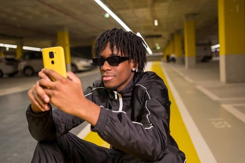 Close-up portrait of an african cool man using phone sitting on a garage