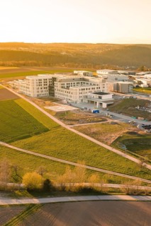 Aerial view of a modern building complex surrounded by fields at sunset, new hospital at the
