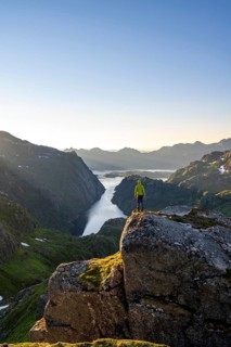 Mountaineer, young man in front of mountain landscape at sunrise, fjord Trollfjord and Raftsund,