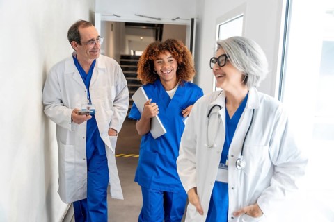 Diverse healthcare team including doctors and a nurse walking together, discussing and smiling in a