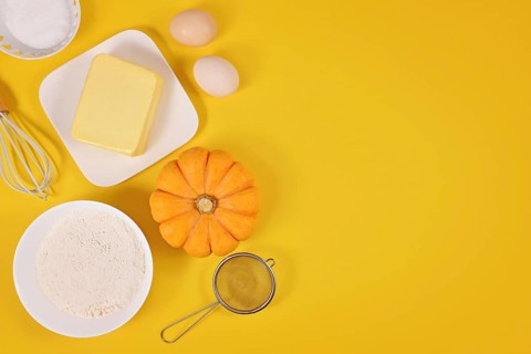 Pumpkin pie ingredients and baking tools on yellow background with copy space