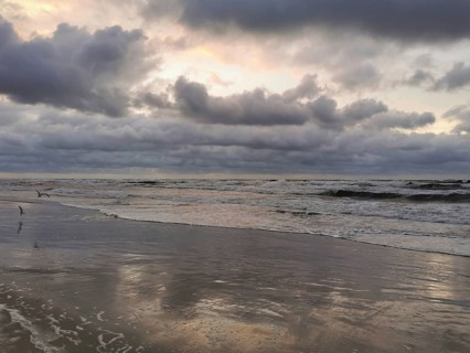 Waves reflect a partly cloudy sky when the sun rises or sets