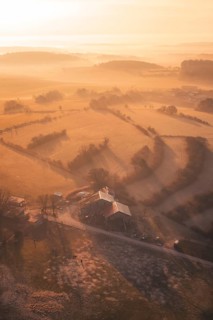 Aerial view of a farmhouse and fields in golden morning fog, Gechingen, Calw district, Germany