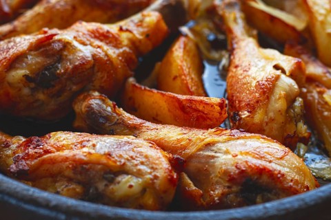 Fried chicken drumsticks with potato slices, in a clay pan, baked in the oven, with spices,