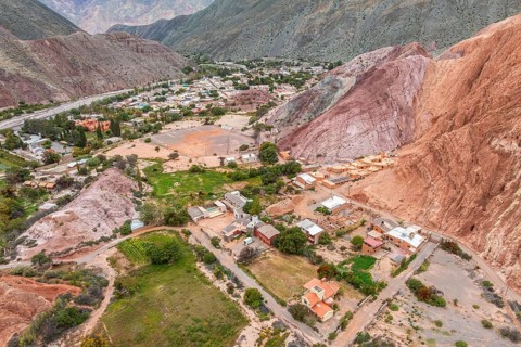 Aerial view capturing the vibrant houses of Purmamarca, Jujuy, nestled against the striking red
