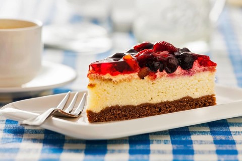 Dessert background, fruit cheese cake on plate with fork and coffee cup on blue checkered
