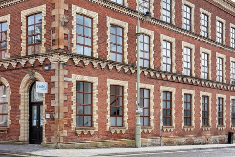 Large historic brick building on a corner with numerous windows and a red façade, Letterkenny