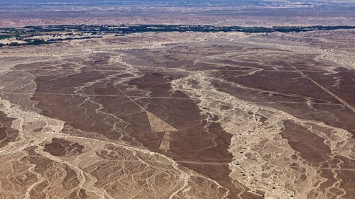 Wide desert landscape seen from the air with withered lines and scattered vegetation, the geoglyphs