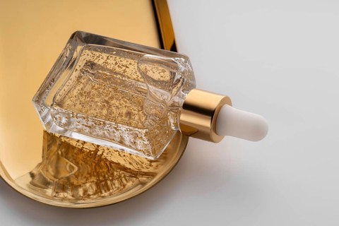 Luxurious anti-aging face serum contained in a stylish glass dropper bottle adorned with shimmering
