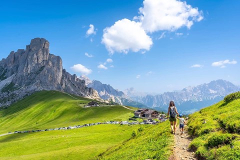 Mother and son walking on a path at giau pass enjoying the beautiful landscape of the dolomites in