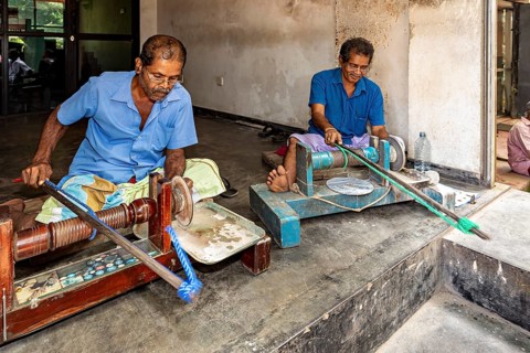 Two men work in a workshop with several machines, the gemstone cutters in the city of Ratnapura in