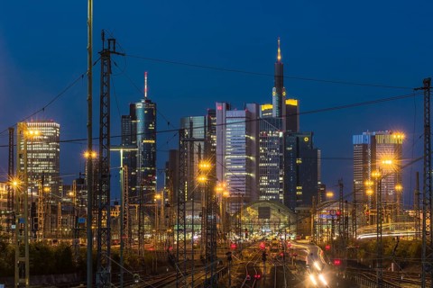 View over rails and moving trains to the luminous main station, in the background the colourful