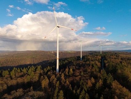 Large wind turbines over wooded hills under a partly cloudy sky, near Schorndorf-Winterbach,