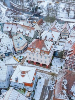 Aerial view of a snow-covered town with traditional half-timbered houses and a river, Nagold, town