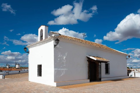 White chapel under a blue sky with clouds, rural architecture and a stone path in the foreground,
