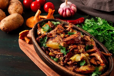 Fried chanterelles with mushrooms, in a clay pan, close-up, top view, selective focus