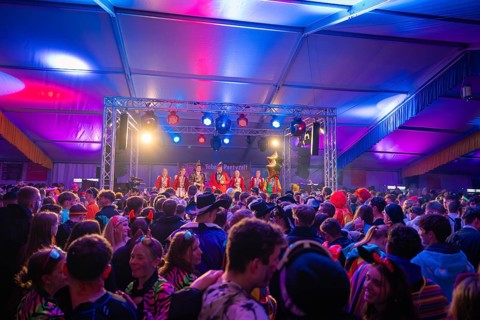 Concert event with stage performance and colourfully dressed people in the audience, carnival,