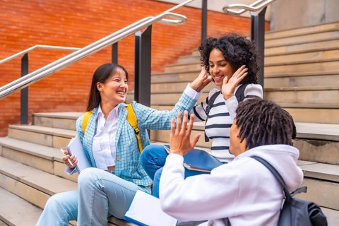 Happy multi-ethnic students sitting in the campus having fun relaxed after class in the university