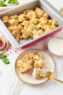 Top view of baked cauliflower in a metal baking tray. Each floret is coated in breadcrumbs and