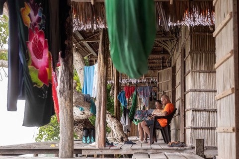 Two tourists, a mature man and woman relaxing at a homestay on Kri Island in the Raja Ampat