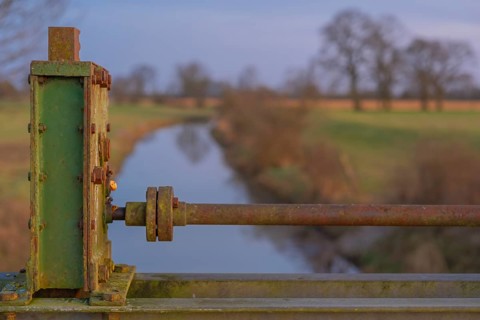 Detailed view of a part of a sluice with a ditch behind it in the evening light