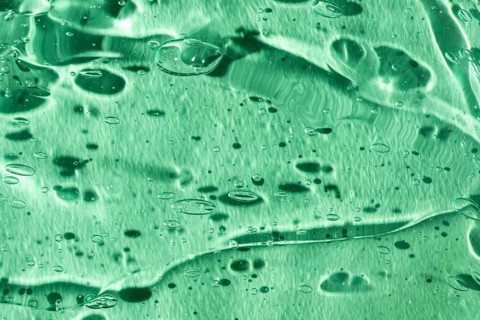 A captivating close-up of a green gel texture, showcasing intricate bubbles and fluid patterns. The
