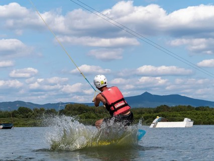 Young man jumping into the water with a wakeboard, water ski and wake park, Stráž pod Ralskem,