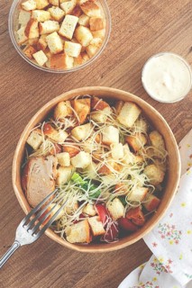Caesar salad in a paper container, take it on the way, with sauce and croutons, on the table,