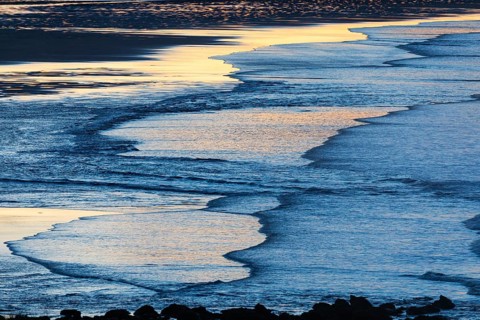 Low tide and gentle waves, at dusk on the North Sea, on the North-east coast of Northumberland,