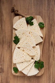 Sliced Georgian cheese, factory grade, on a wooden board, top view