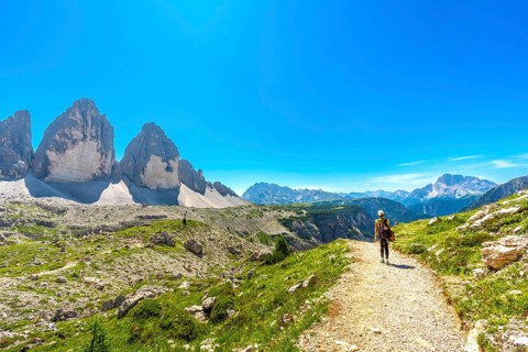 Tourist walking on a mountain path near tre cime di lavaredo in the dolomites, italy, enjoying the