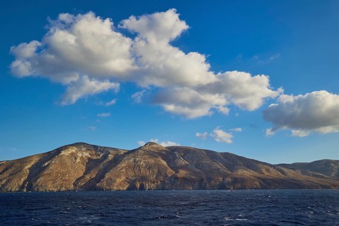 Rocky mountain landscape of an island under a blue sky and light clouds, Kassos Island,
