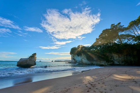 Coast with sandy beach and surrounding rocks, with clouds in the sky and peaceful atmosphere,
