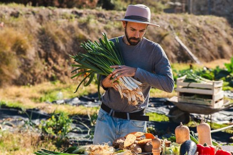 A man outdoors, preparing calsots for a traditional Catalan calsotada. The fresh onions symbolize