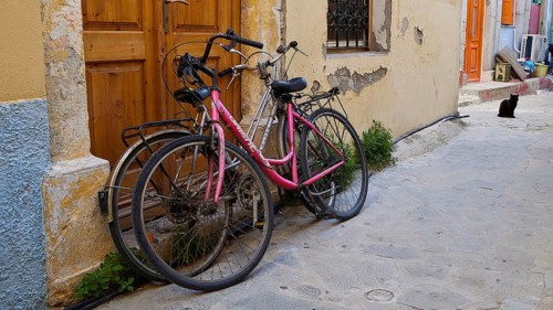 Two old bicycles standing against a yellow wall in a narrow street of the old town, Symi Town,