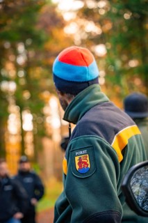 Person in forest jacket and colourful cap looking into the autumn forest, tree planting campaign,