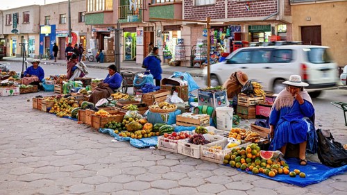 Women selling fresh fruit from roadside stalls during daylight hours, The Uyuni street market in