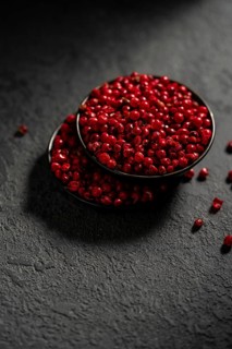 From above, a striking image showing a bowl filled with vibrant red peppercorns placed on a