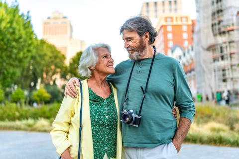 Frontal portrait of a couple of senior tourists standing looking at each other in the city