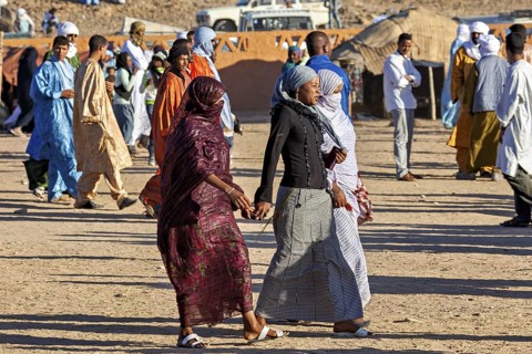 A lively scene at a market with many people in traditional costumes, veiled woman at the
