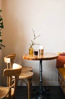 A cozy cafe corner featuring a wooden table with a decorative vase and drinks, surrounded by wooden