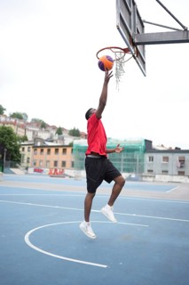 African american basketball player umping and scoring training in an outdoor urban court