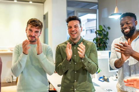 Multi ethnic business team clapping hands, celebrating success in a modern office, showing